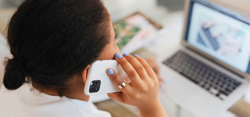 Woman preparing for her disability hearing over phone while reviewing documents on laptop