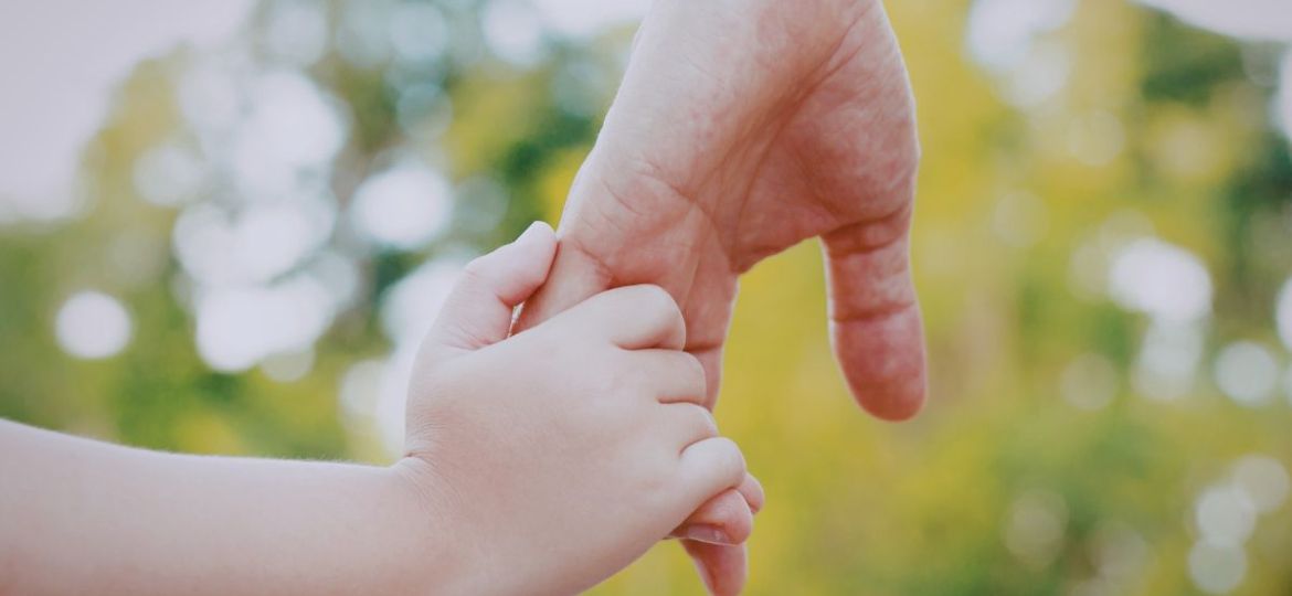 The father holds his son's hand.