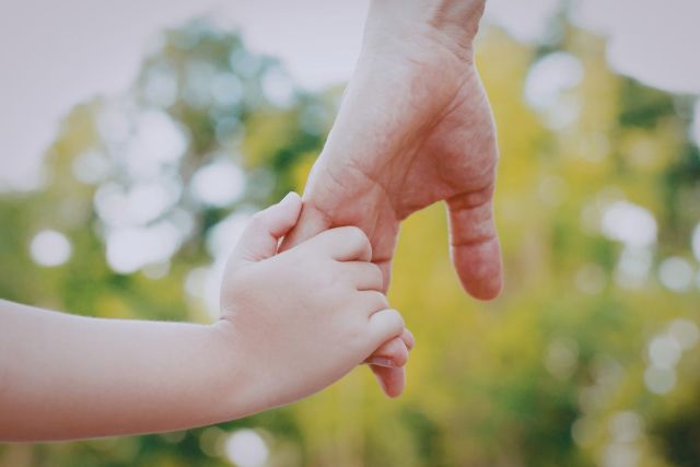 The father holds his son's hand.