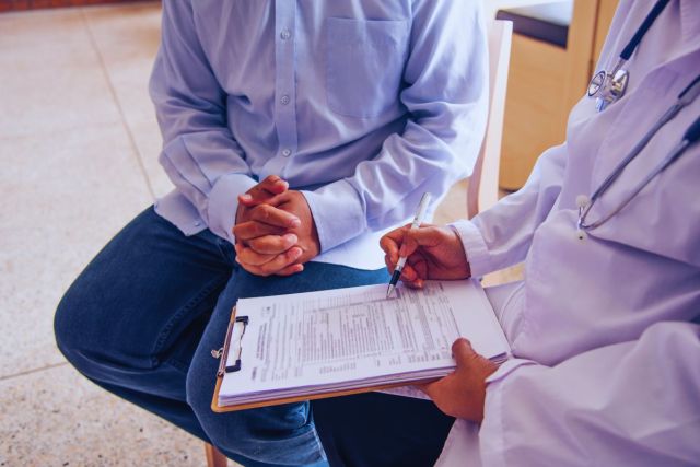 The man is undergoing a workers' comp independent medical exam.